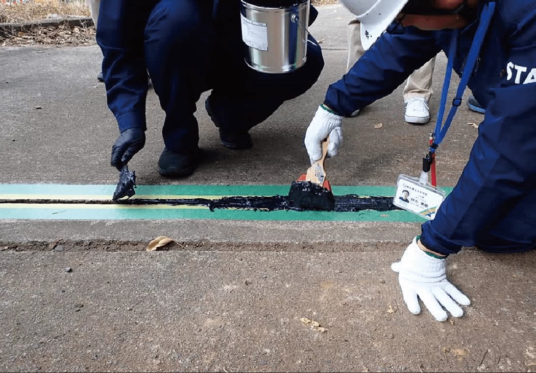 ▲職員が橋の隙間を覆い、漏水を防ぐための補修を行う。