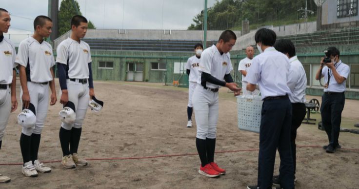 ビニールテープで補修したボールを高校の硬式野球部に手渡す特別支援学校の生徒ら。